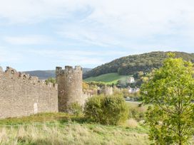 A castle wall with a tower and a hill in the background at Riverside Cottage Conwy