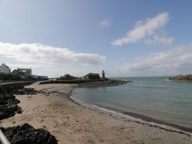 A beach with a lighthouse and houses at Ellies House in Stranraer