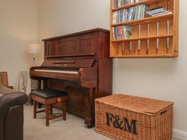 A living room with a piano and a bookshelf at Castle Terrace in Penrith