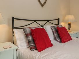 A bedroom with a black bed frame and red cushions at Castle Terrace in Penrith
