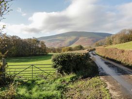 A road leading to a gate with a field and mountain at Castle Terrace in Penrith