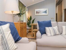 A living room with a sofa and dining area at 5 Waterside Wood Troutbeck Bridge