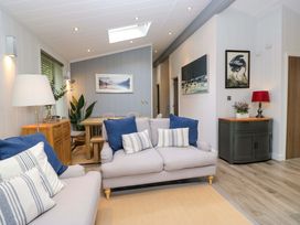 A living room with a sofa and dining table at 5 Waterside Wood Troutbeck Bridge