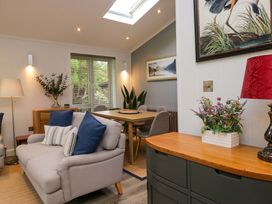 A living room with a sofa, dining table, and wall art at 5 Waterside Wood in Troutbeck Bridge