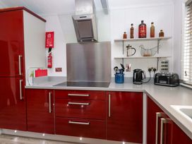 A kitchen with red cabinets and stainless steel appliances at 5 Waterside Wood Troutbeck Bridge