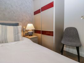 A bedroom with a bed, lamp, nightstand, chair, and wardrobe at 5 Waterside Wood, Troutbeck Bridge