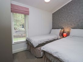 A bedroom with two beds and a window at 5 Waterside Wood in Troutbeck Bridge