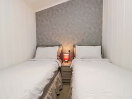 A bedroom with two single beds and a lamp at 5 Waterside Wood Troutbeck Bridge