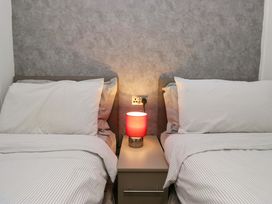 A bedroom with two beds and a lamp on a nightstand at 5 Waterside Wood Troutbeck Bridge