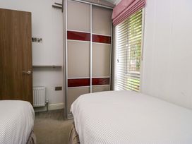 A bedroom with two beds and a wardrobe at 5 Waterside Wood in Troutbeck Bridge