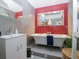 A bathroom with a bathtub, sink, and mirror at 5 Waterside Wood Troutbeck Bridge