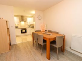 A dining room featuring a table and chairs with an open kitchen at Heulfan Conwy