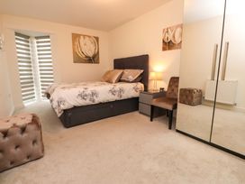 A bedroom with a bed, nightstand, lamp, and chair at Heulfan in Conwy
