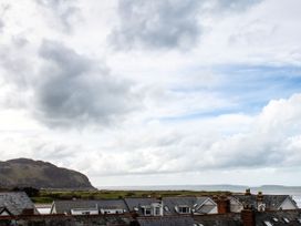 A view of rooftops and the sea under a cloudy sky at Heulfan Conwy