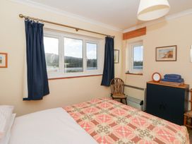A bedroom with a bed and windows at Bryncyn in Newport, Pembrokeshire