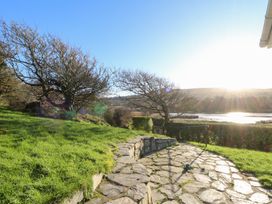 A garden with a stone path and trees at Bryncyn in Newport, Pembrokeshire