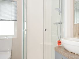 A bathroom featuring a toilet, shower enclosure, and sink at 2 Summerleaze in Bude