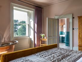 A bedroom with a bed and door leading to a bathroom at The Country House Cumbria Castle Carrock
