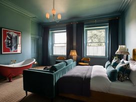 A bedroom with a bathtub, sofa, and bed at The Country House Cumbria Castle Carrock