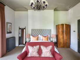 A bedroom with a double bed and red sofa at The Country House Cumbria Castle Carrock