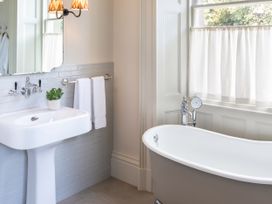 A bathroom with a bathtub, sink, and towels at The Country House Cumbria in Castle Carrock