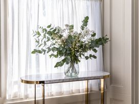 A vase with flowers on a table by the window at The Country House Cumbria Castle Carrock