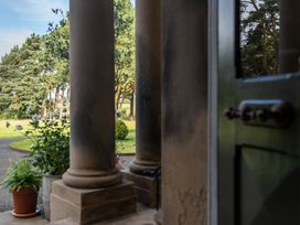 A view from a porch with pillars and plants leading to a garden at The Country House Cumbria, Castle Carrock