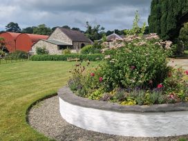 A garden with flowers and a stone wall at Secret Garden Cottage in Ciliau Aeron near Aberaeron