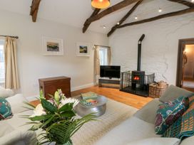 A living room with a television and wood stove at Secret Garden Cottage in Ciliau Aeron near Aberaeron