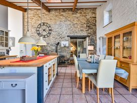 A kitchen with a dining table and stone wall at The Old Farm House near Pelynt