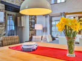 A dining room table with a vase of flowers at The Old Farm House near Pelynt