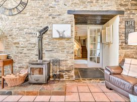 A living room with a stove and wooden table at The Old Farm House near Pelynt