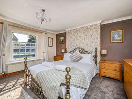 A bedroom with a bed and wooden furniture at The Old Farm House near Pelynt