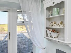 A shelf with decorative items and a window in a bathroom at The Old Farm House near Pelynt