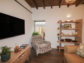 A living room with a television, chair, shelf, and plants at The Loft in Glenmore, County Kilkenny