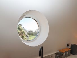 A circular window in a kitchen looking out to a garden at Hilldown Granary near Bow