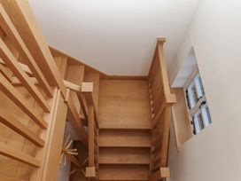 A wooden staircase with a railing and a window at Hilldown Granary near Bow