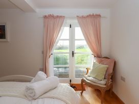 A bedroom with a bed and a chair at Hilldown Granary near Bow