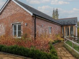 A brick exterior of a house with a pathway and plants at Hilldown Cott in Crediton