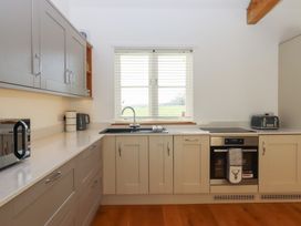 A kitchen with a sink, microwave, and cabinets at Hilldown Cott near Bow