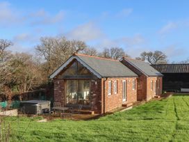 A brick house with a patio and hot tub at Hilldown Cott near Bow