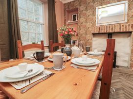 A dining room with a wooden table set for a meal at Daisy cottage in Pickering