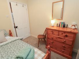 A bedroom with a bed, dresser, chair, and a lamp at Daisy cottage, Pickering