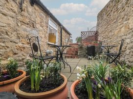 A garden with potted plants and seating area at Daisy cottage in Pickering