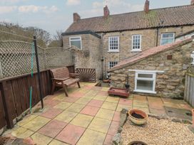 A garden with a stone wall and a wooden bench at Daisy cottage in Pickering