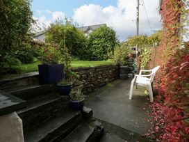 A garden with a stone wall and chair at Noddfa in Penmachno