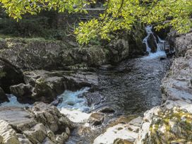 A river flowing over rocks with a waterfall at Noddfa Penmachno