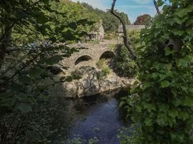 A bridge over a river in a village surrounded by trees at Noddfa in Penmachno