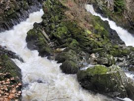 A stream flowing over rocks with moss in Noddfa Penmachno