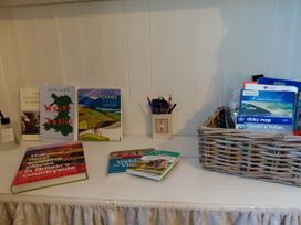 A shelf with books and a basket with maps at Noddfa in Penmachno